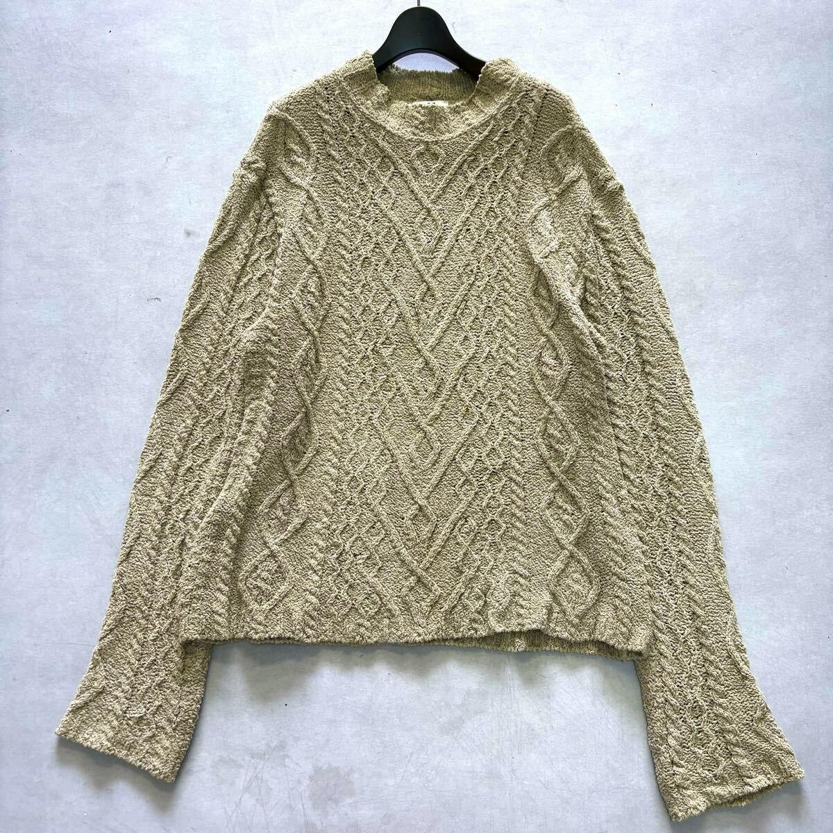 Front view of a beige oversized cable-knit long-sleeve Dries Van Noten sweater laid flat on a light background.