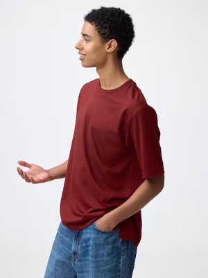 A model wearing a red T-shirt and blue jeans shown in profile against a white background.
