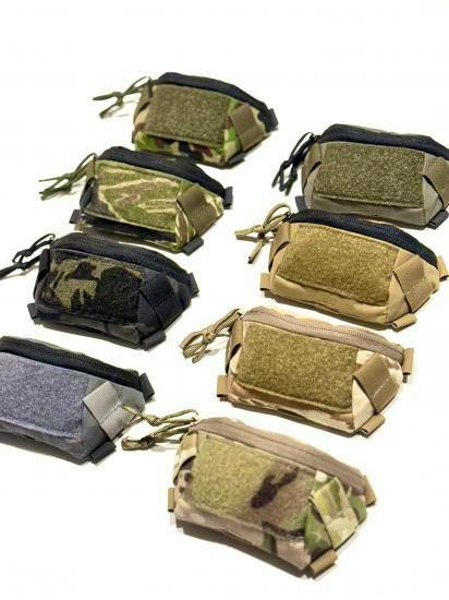 Several nylon ducktail helmet pouches in different camouflage and solid colors arranged on a white background.