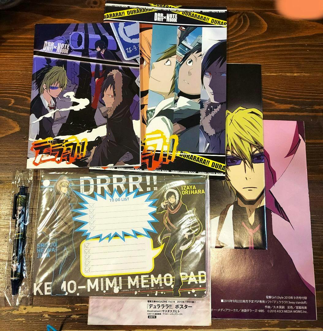 Durarara!! goods set arranged on a wooden table showing multiple posters, a memo pad, and a pen.
