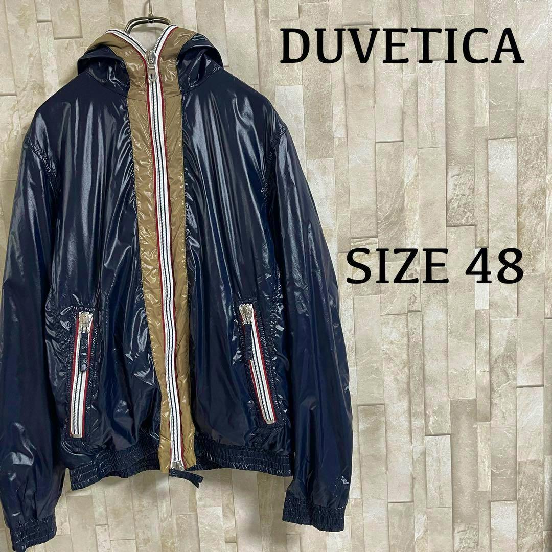 Front view of a navy DUVETICA nylon men's jacket (size 48) hanging on a hanger against a tiled wall.