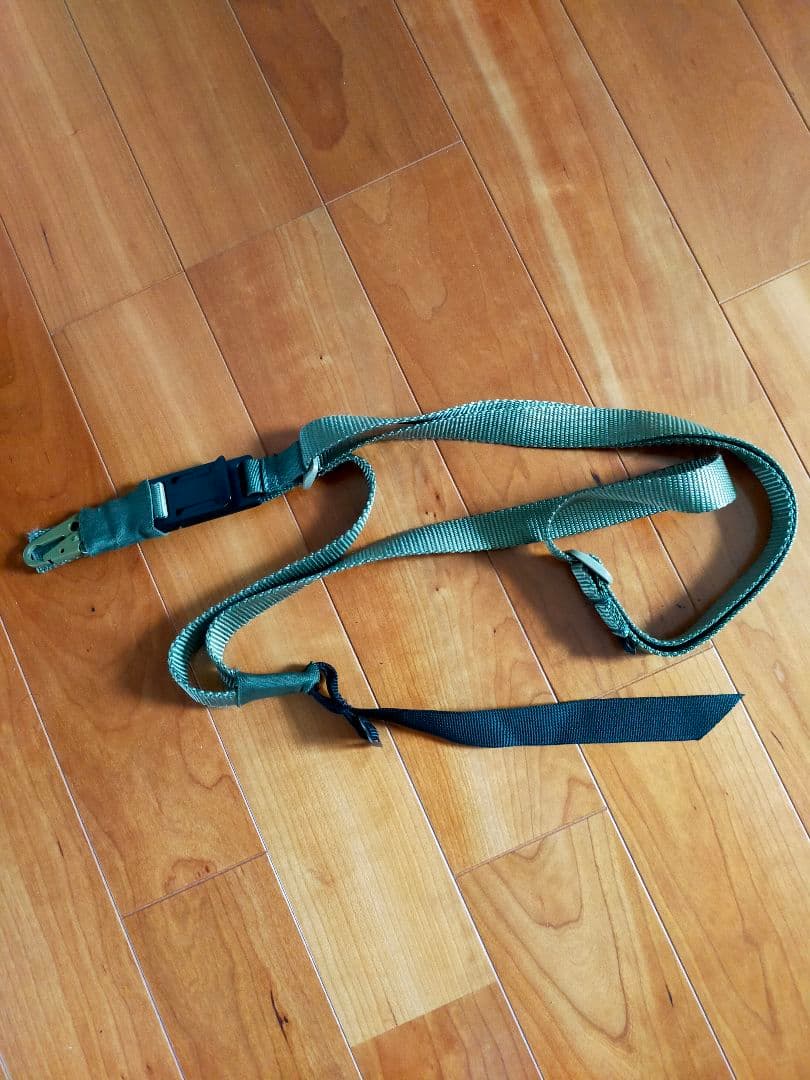 Green nylon 3-point sling laid out on a wooden floor.
