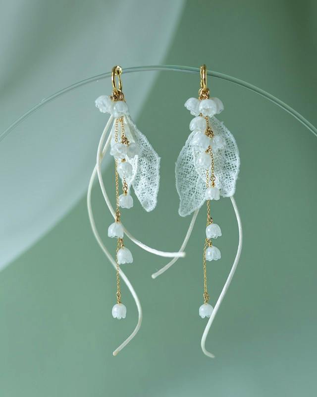 Pair of 14kgf earrings featuring white lace-like leaf elements, gold chains, and small white bead dangles.