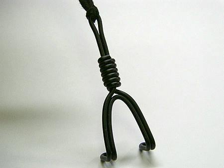 Close-up photo of a black plastic nose hook suspended by its cord against a white background.