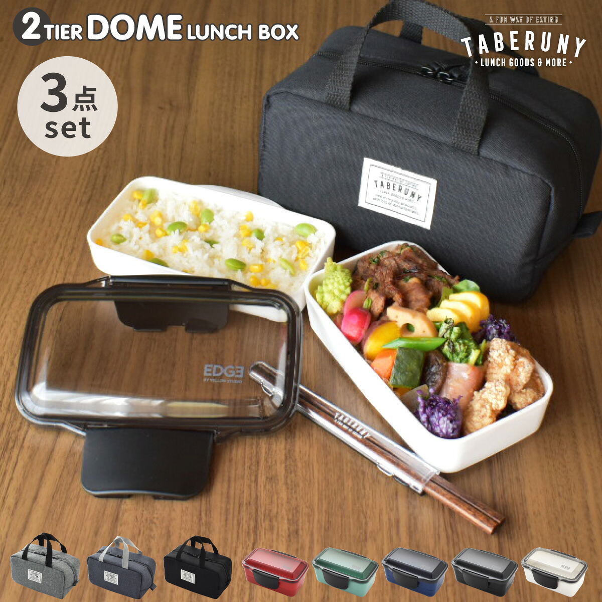 Two-tier dome lunch box set shown with a clear lid, two white bento tiers (one filled with food), a black insulated lunch bag, and a pair of chopsticks on a wooden surface.