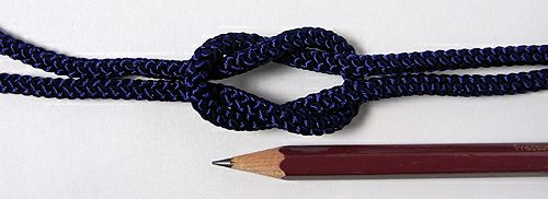 A navy Edo braided cord (5 mm) tied in a knot laid next to a pencil for scale.