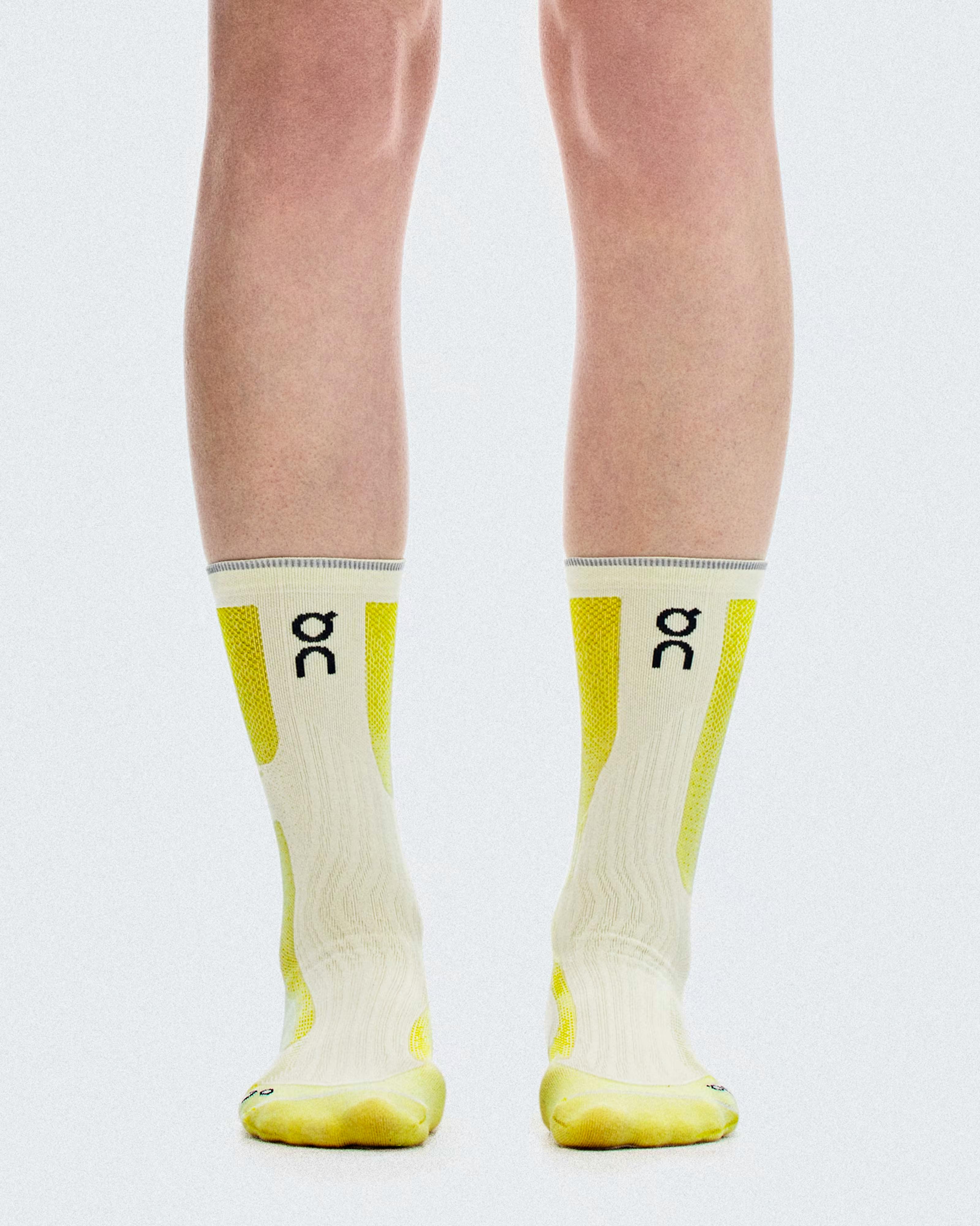 Front view of the Elite Run Sock High Hyper yellow-and-white high socks worn on both legs, showing calves to toes.