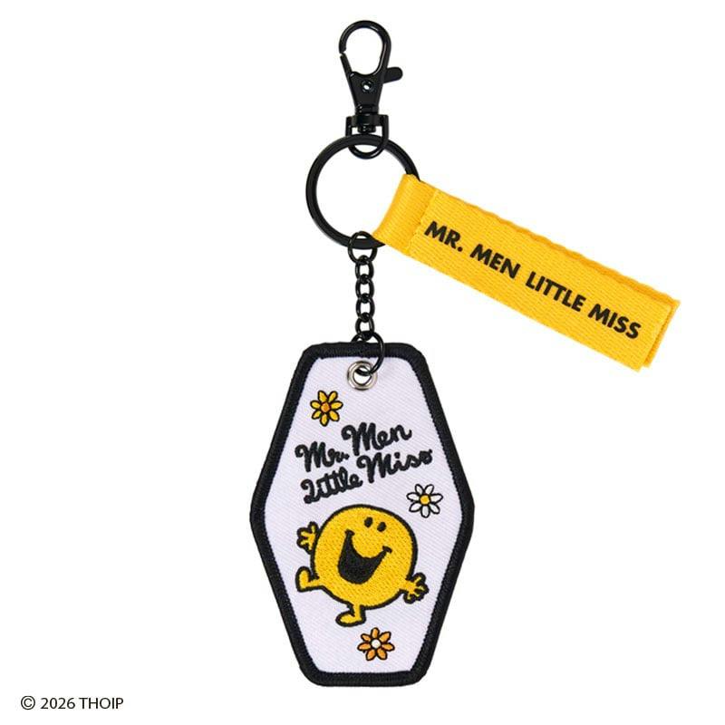 Embroidered keychain with a white hexagonal embroidered charm showing a yellow smiling character and flowers, attached to a yellow fabric tag reading "MR. MEN LITTLE MISS" and a black metal ring and clasp.