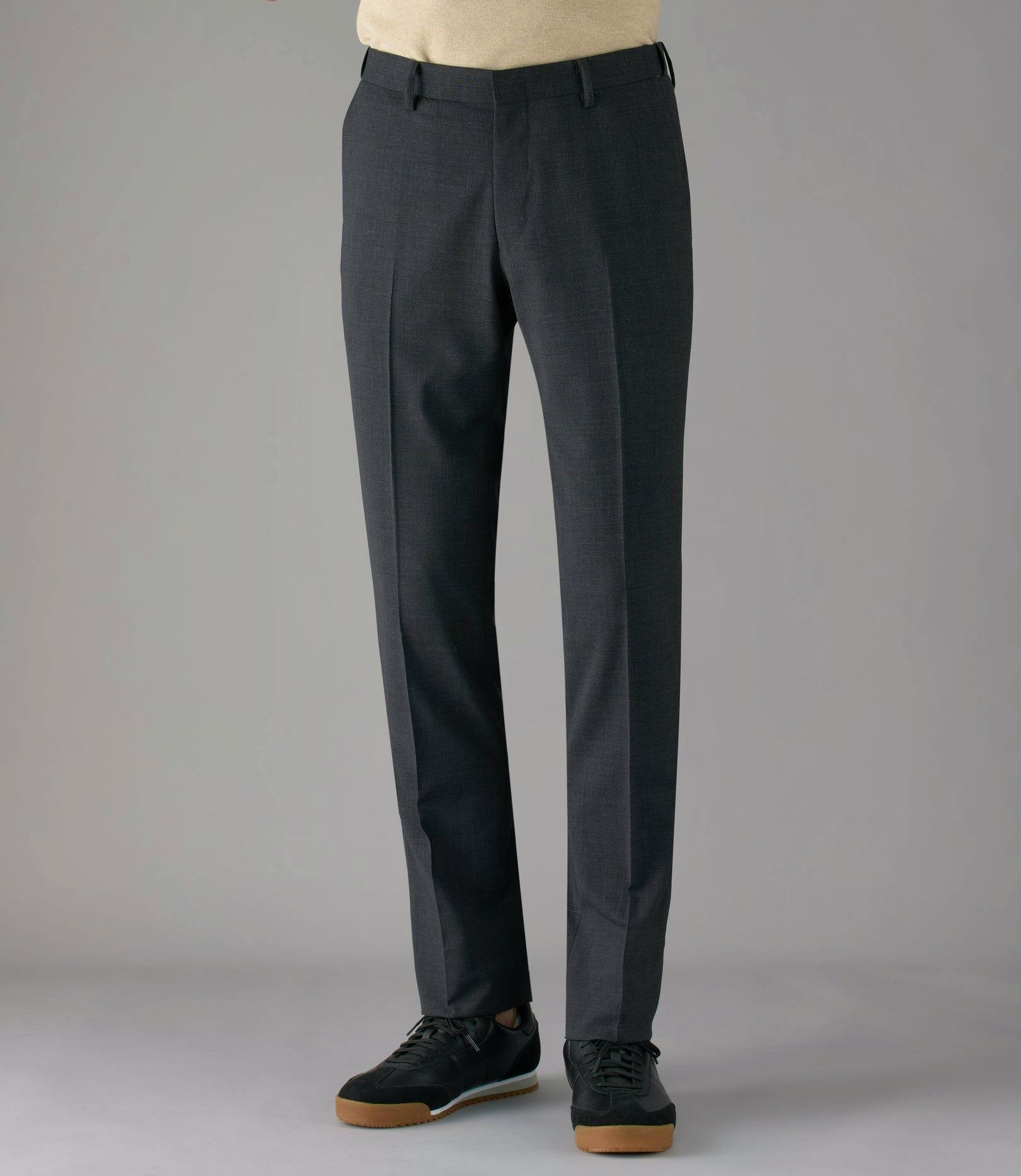 Model wearing men's dark gray polyester dress pants shown full length from waist to shoes.