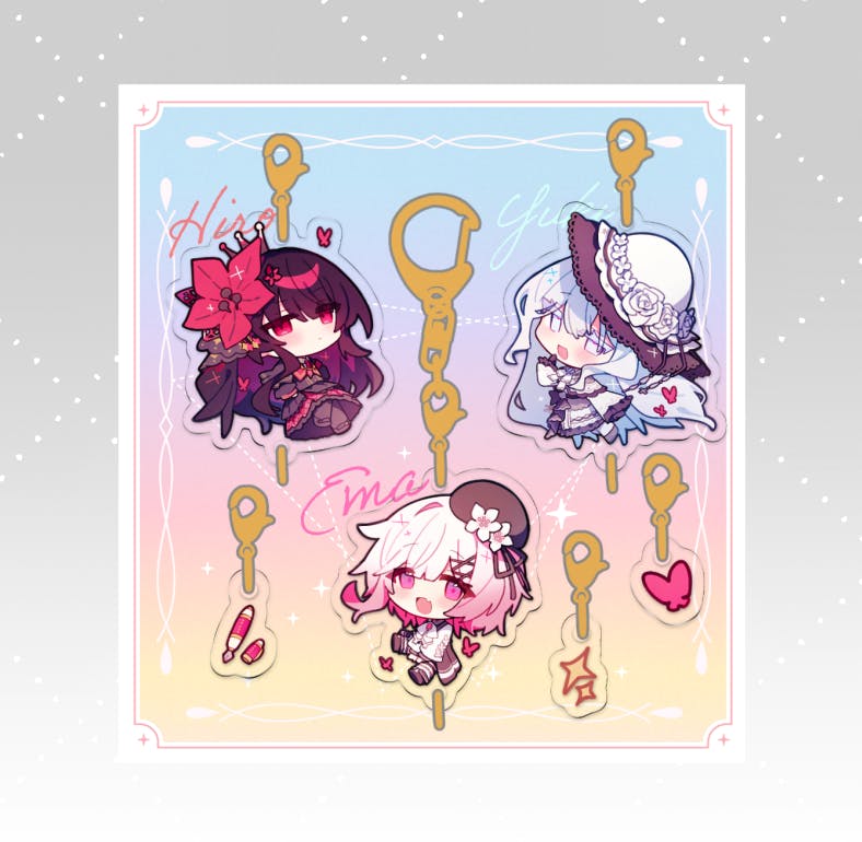 A pastel backing card displaying three illustrated acrylic keychain charms (chibi characters) and small accessory pieces.