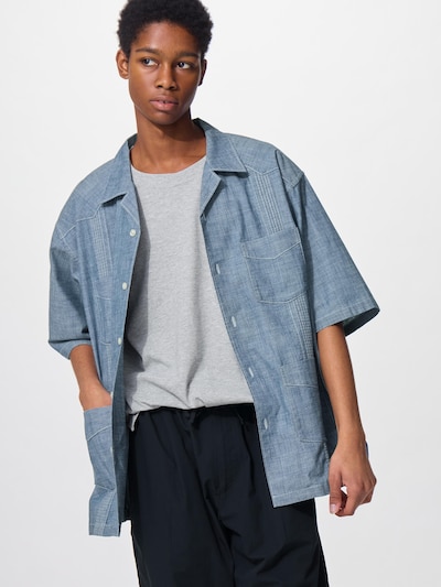 A model wearing the blue short-sleeve cotton Cuban shirt.