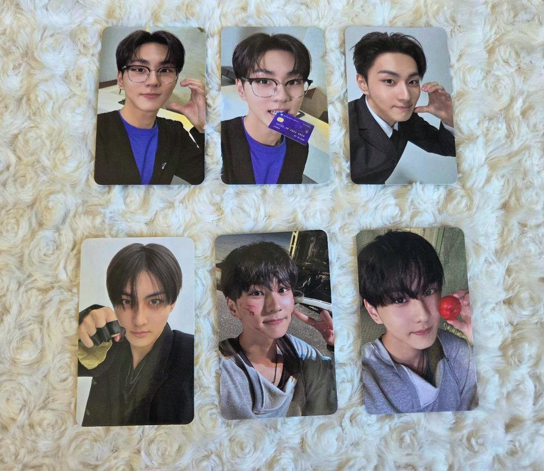 Six rectangular photocard fronts showing portrait photos of a young man, arranged in two rows on a white fuzzy surface.