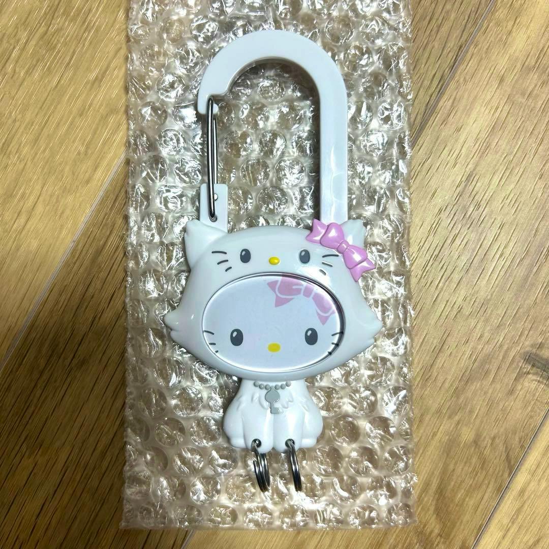 Front view of a white plastic cat-shaped carabiner keychain with a pink bow and two metal split rings on bubble wrap.