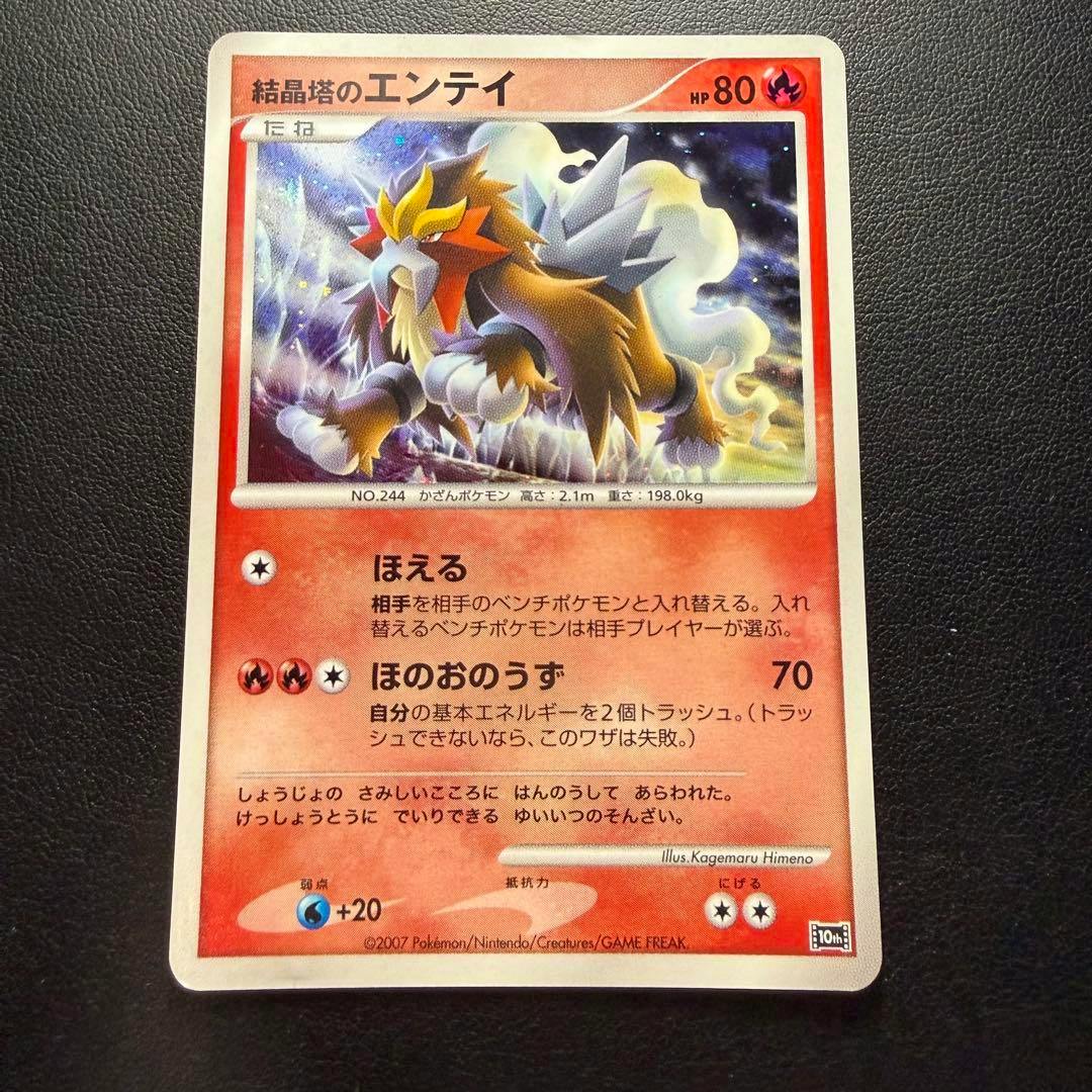 A photographed trading card titled 結晶塔のエンテイ (Entei) showing the full card on a black textured background.