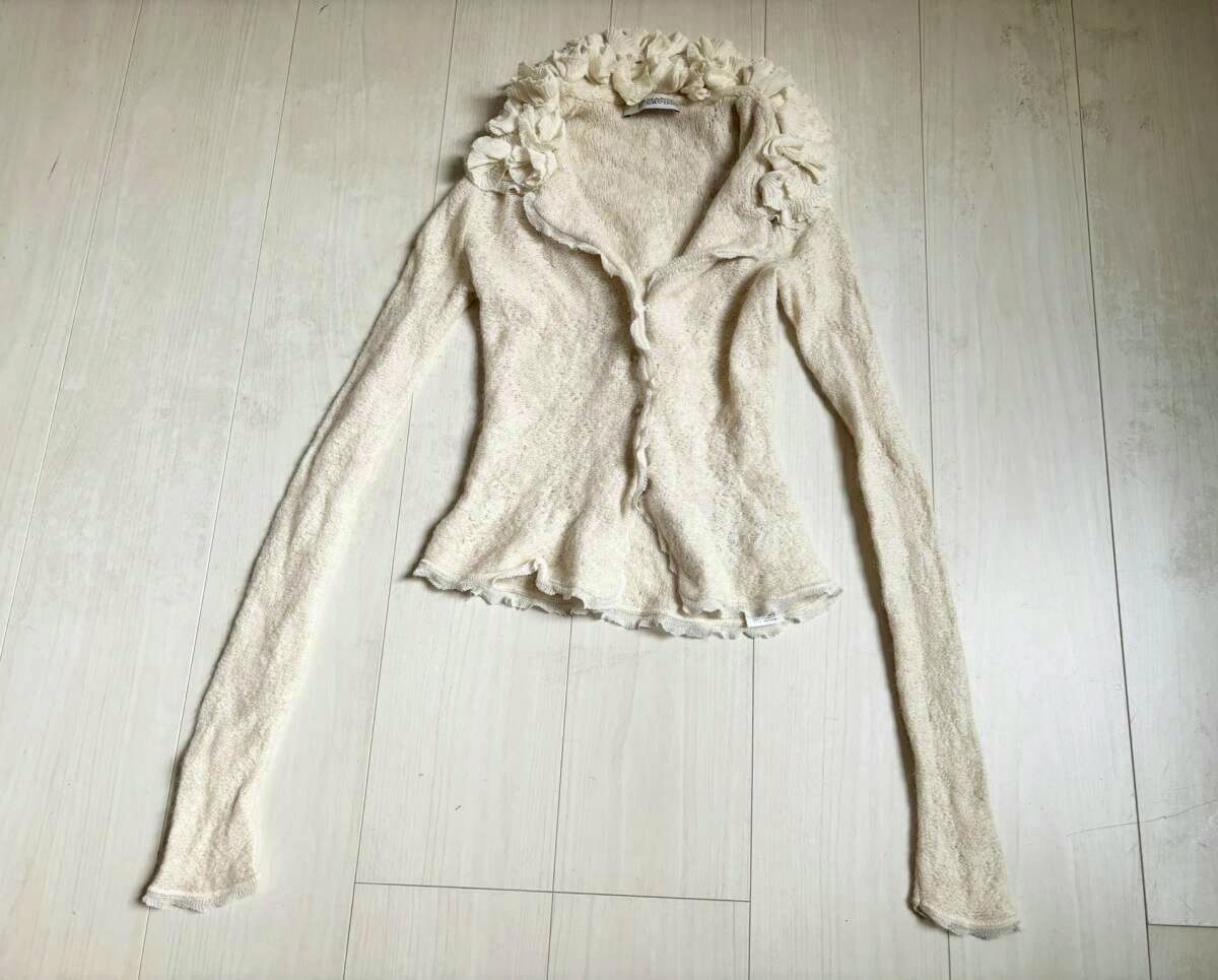 Ivory ERMANNO SCERVINO frilled knit cardigan laid flat on a light wooden floor.