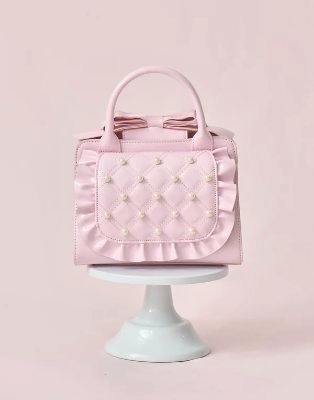 Black synthetic leather Eternity love mellfy bag with quilted, pearl-studded front, ruffled trim and top handle on a white background.