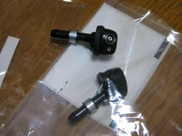 Two car air valve units shown in a clear plastic bag on a wooden surface.