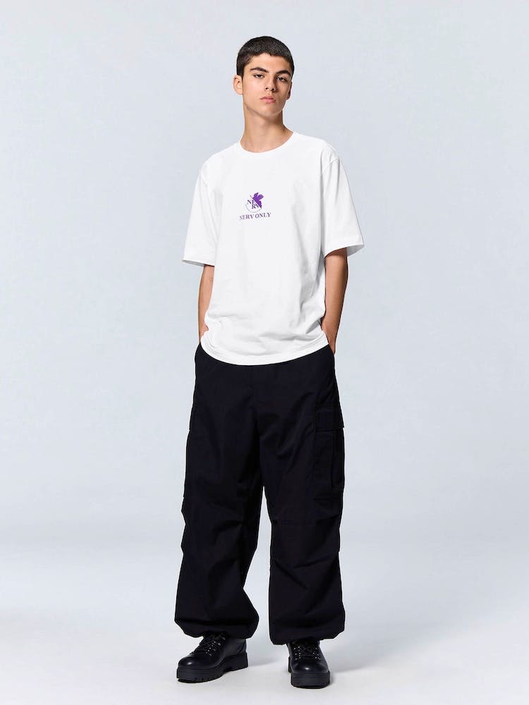 Model wearing a white Evangelion graphic T-shirt with a small purple chest graphic, shown full-length.