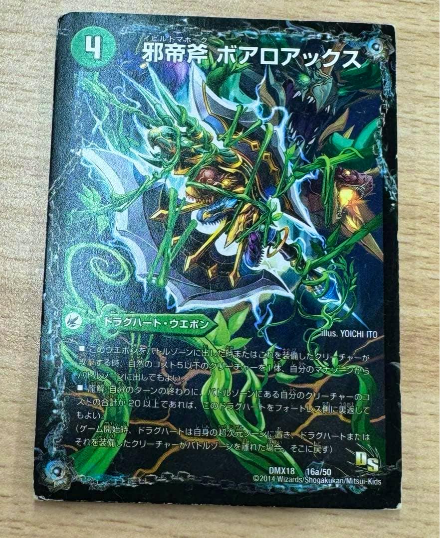 Front of the trading card '邪帝斧 ボアロアックス DMX18 16a/50' photographed on a wooden surface, showing the card artwork and Japanese text.
