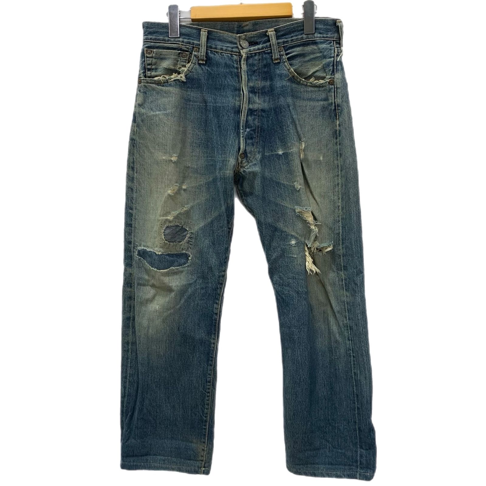 Front view of men's blue distressed denim jeans hanging on a hanger.