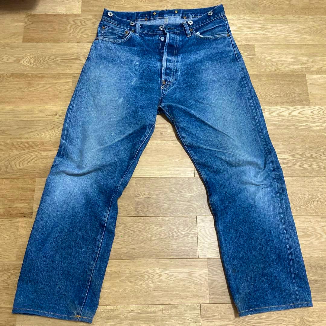 Front view of the EVISU men's blue denim jeans (W33) laid flat on a wooden floor.
