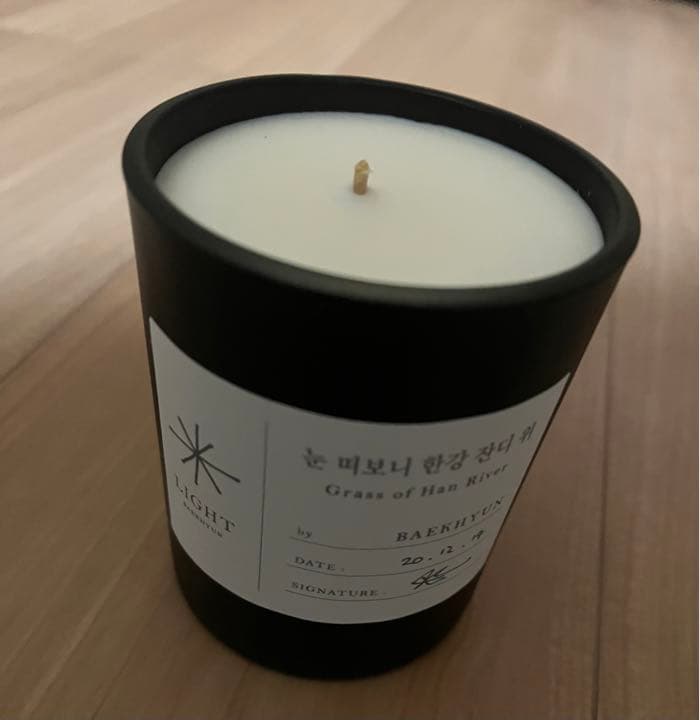 Black jar candle showing white wax and a label reading 'Grass of Han River' by BAEKHYUN.