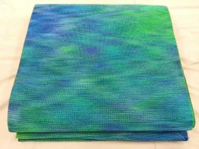 Folded blue-green obi (obi for kimono) laid on a light surface.