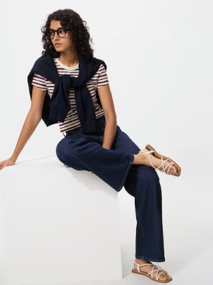 A model seated wearing dark blue wide straight jeans.
