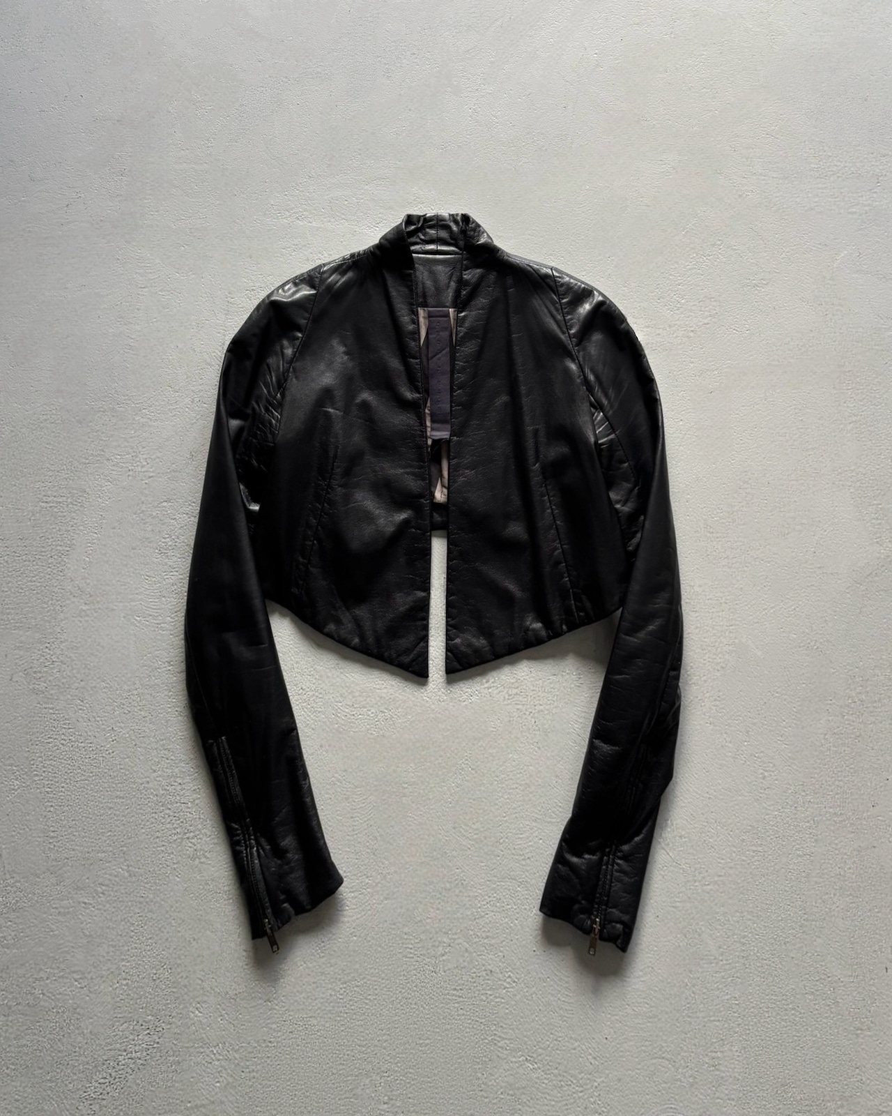 Black sheepskin leather panelled jacket laid flat on a light background.