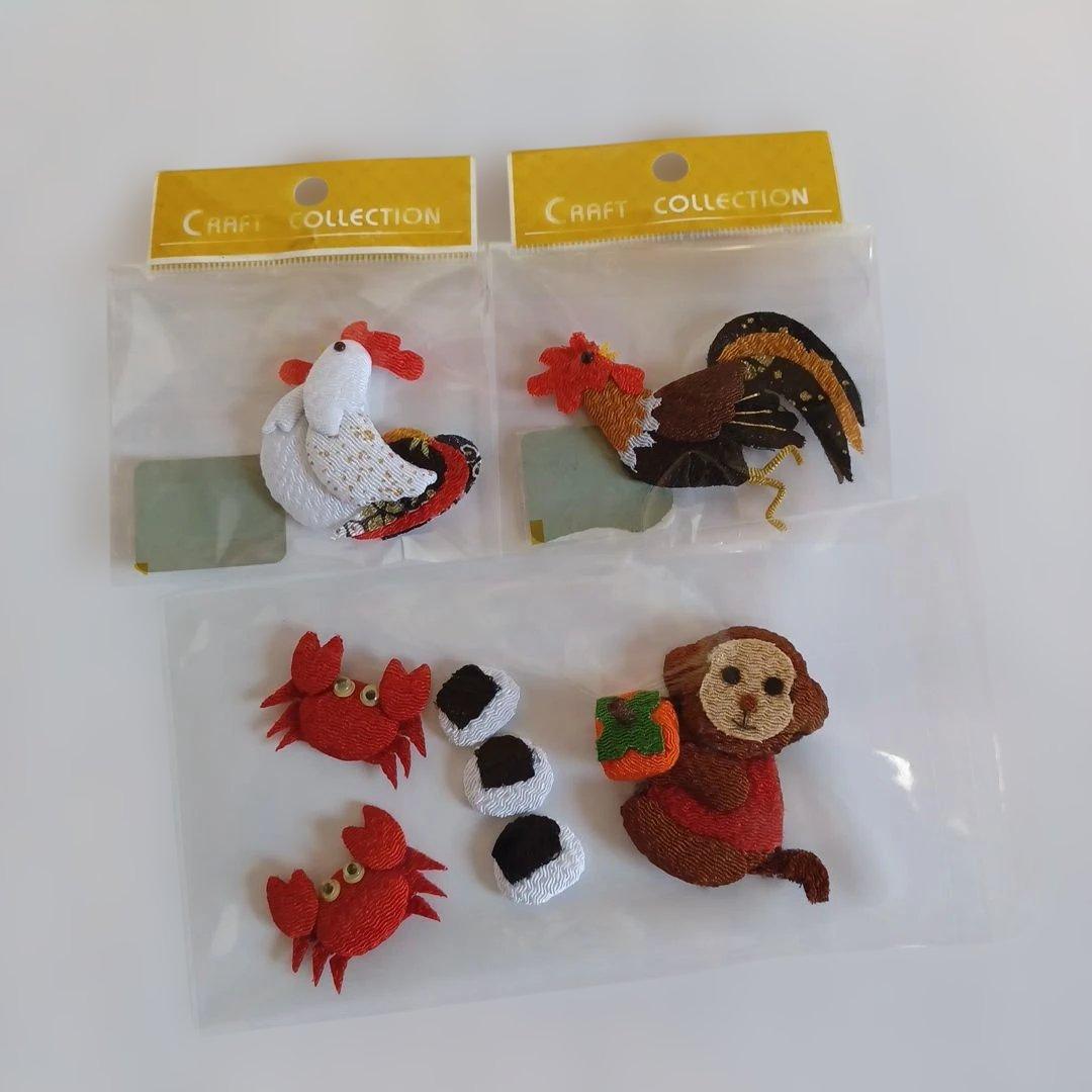 Clear photo of three fabric ornament sets in plastic bags: a white hen, a brown rooster, and a monkey-and-crab set with small rice-ball pieces.
