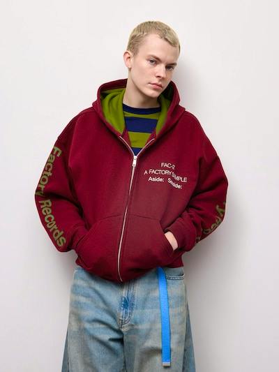 Model wearing a maroon full-zip heavyweight sweatshirt hoodie with Factory Records text on the sleeve and chest.