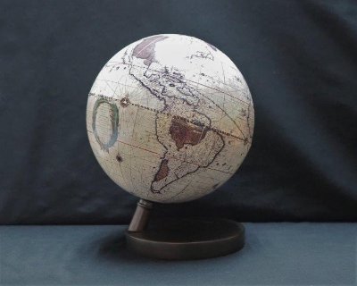 A plastic globe on a small dark stand showing the Americas against a dark background.