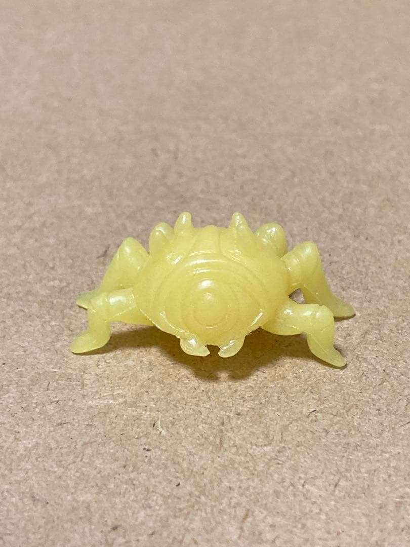A small yellow eraser shaped like Gohma from The Legend of Zelda placed on a brown surface.