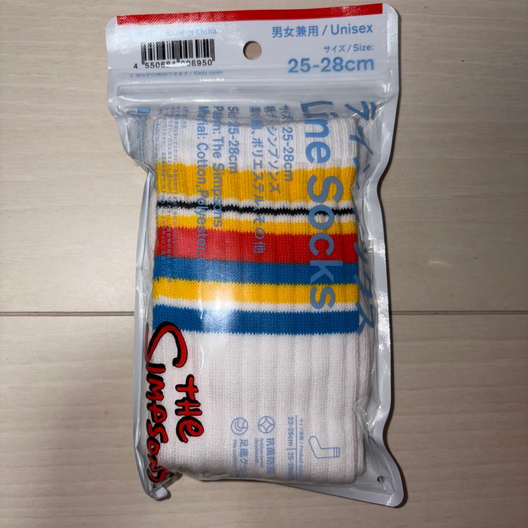 Packaged white crew socks with yellow, red, blue and black stripes, visible through clear plastic packaging labeled 25-28cm.