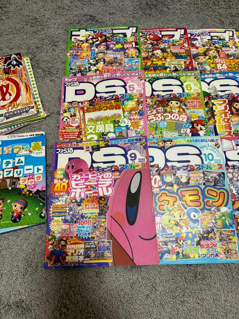 Several issues of the magazine 'ファミ通キューブ＋アドバンス' from 2006 laid out on a gray carpet showing their colorful front covers.
