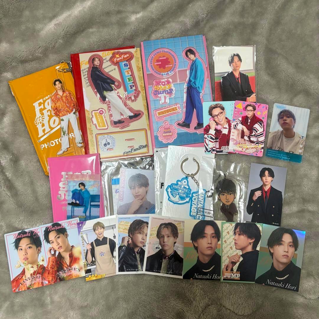 A flat-lay photo of FANTASTICS 堀夏喜 merchandise showing acrylic stands, photo cards, keychains, and other collectible goods arranged on a gray fuzzy surface.