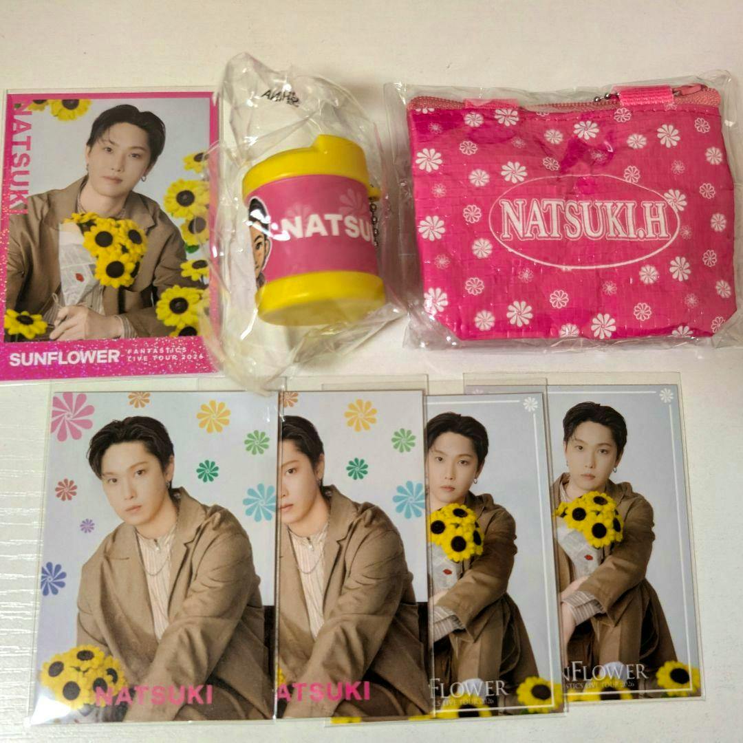 A spread of SUNFLOWER merchandise including multiple photocards, a small pink pouch, and a keychain, showing a male artist in a brown jacket holding sunflowers.