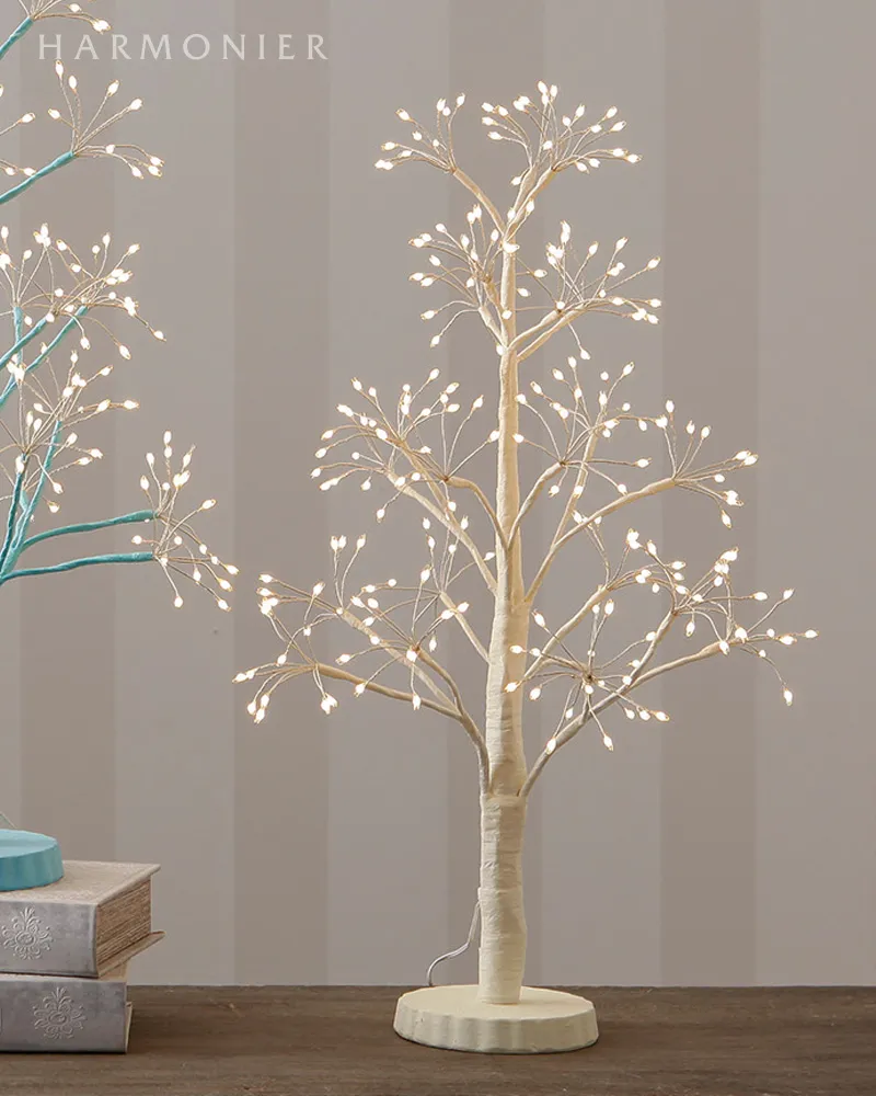 Lit 60cm white fantasy tree desk lamp on a round base placed on a tabletop.