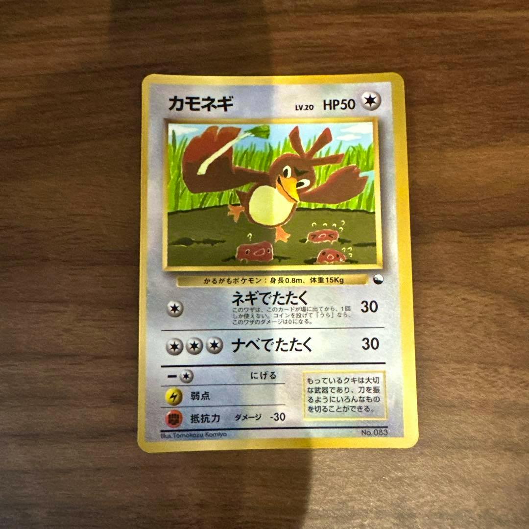 Front of the カモネギ trading card showing the character illustration, Japanese text and HP50, on a wooden surface.