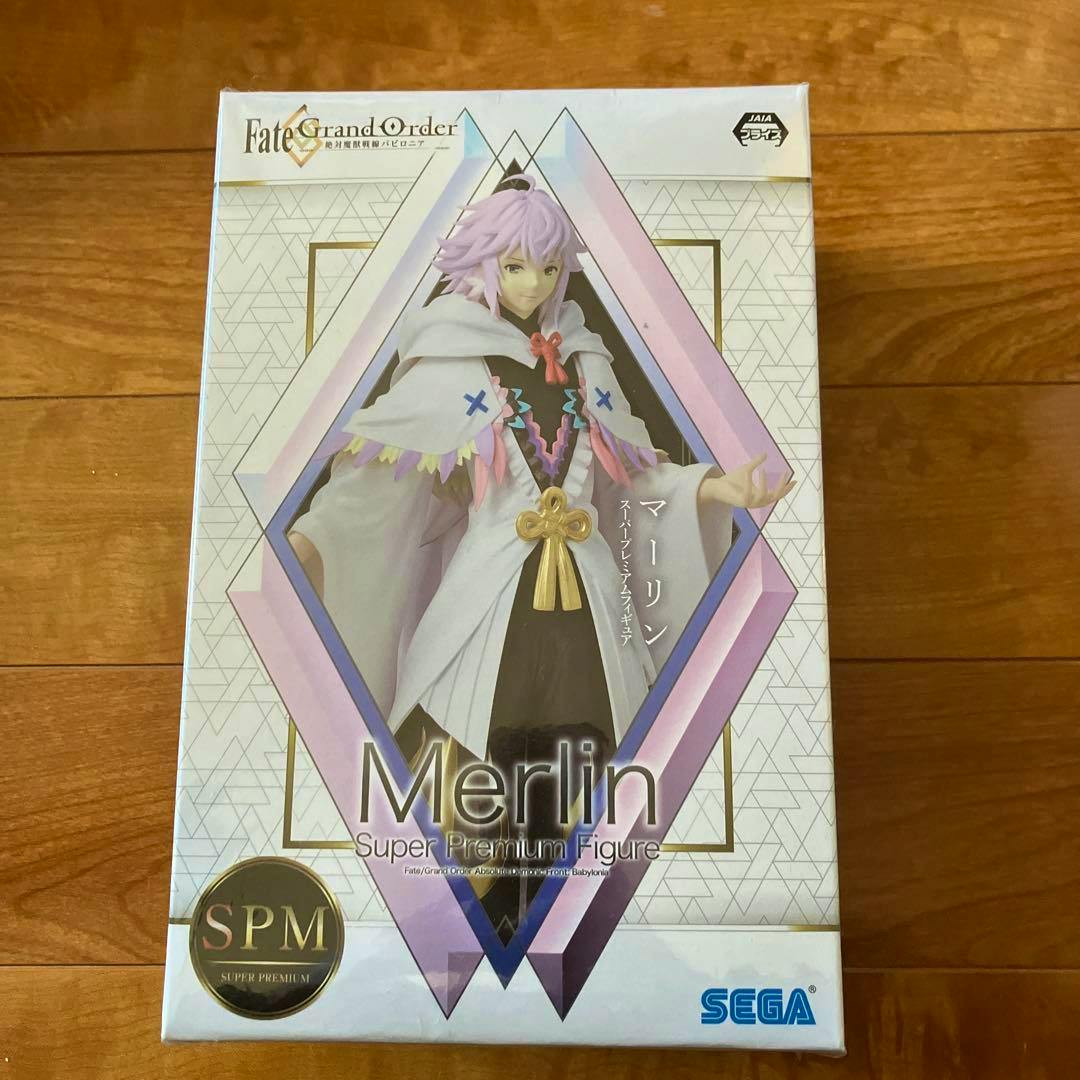 Front of the boxed Fate/Grand Order "Merlin" Super Premium Figure by SEGA shown on a wooden surface.