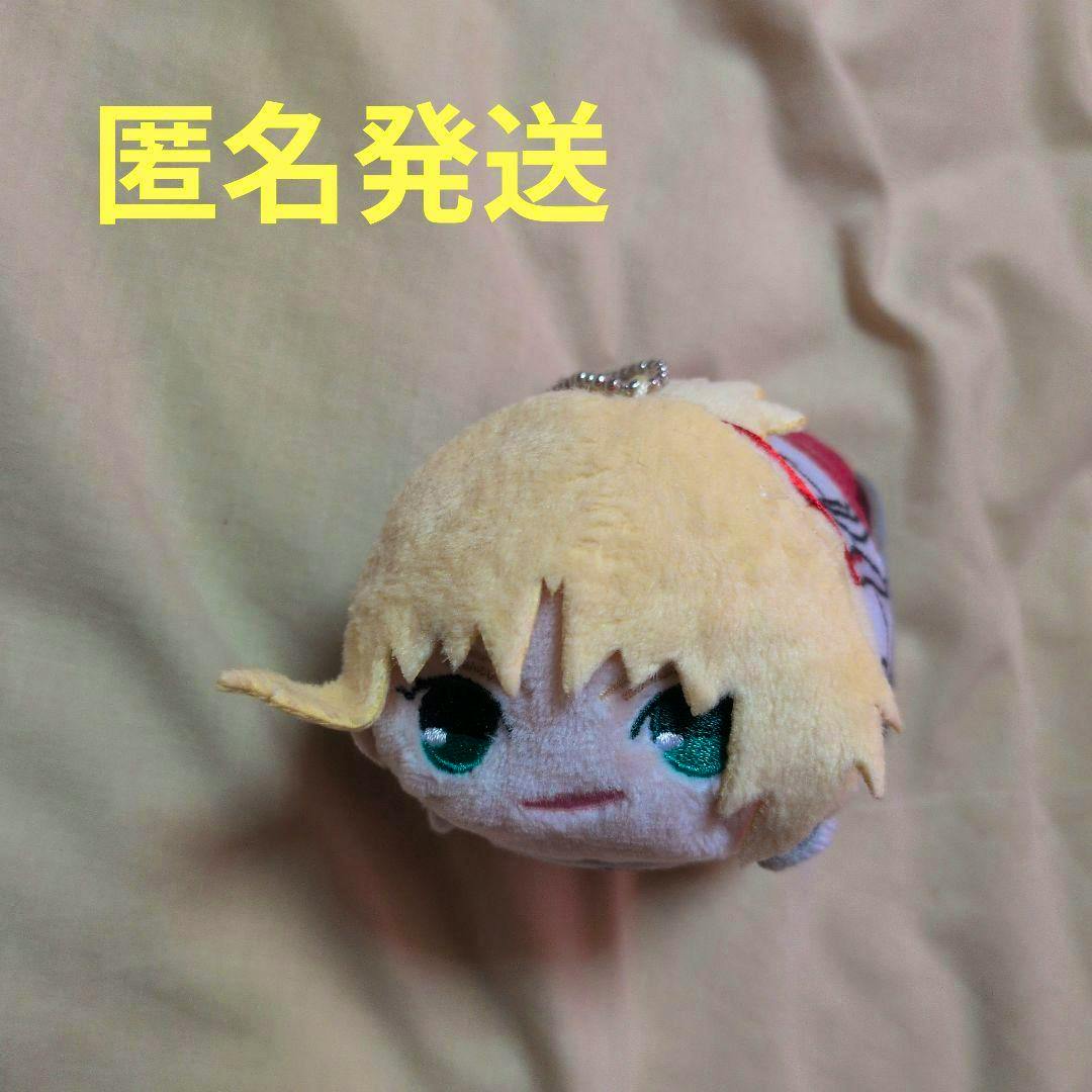 Front-facing plush toy keychain of FGO Mordred showing blonde hair and embroidered green eyes on a beige background.