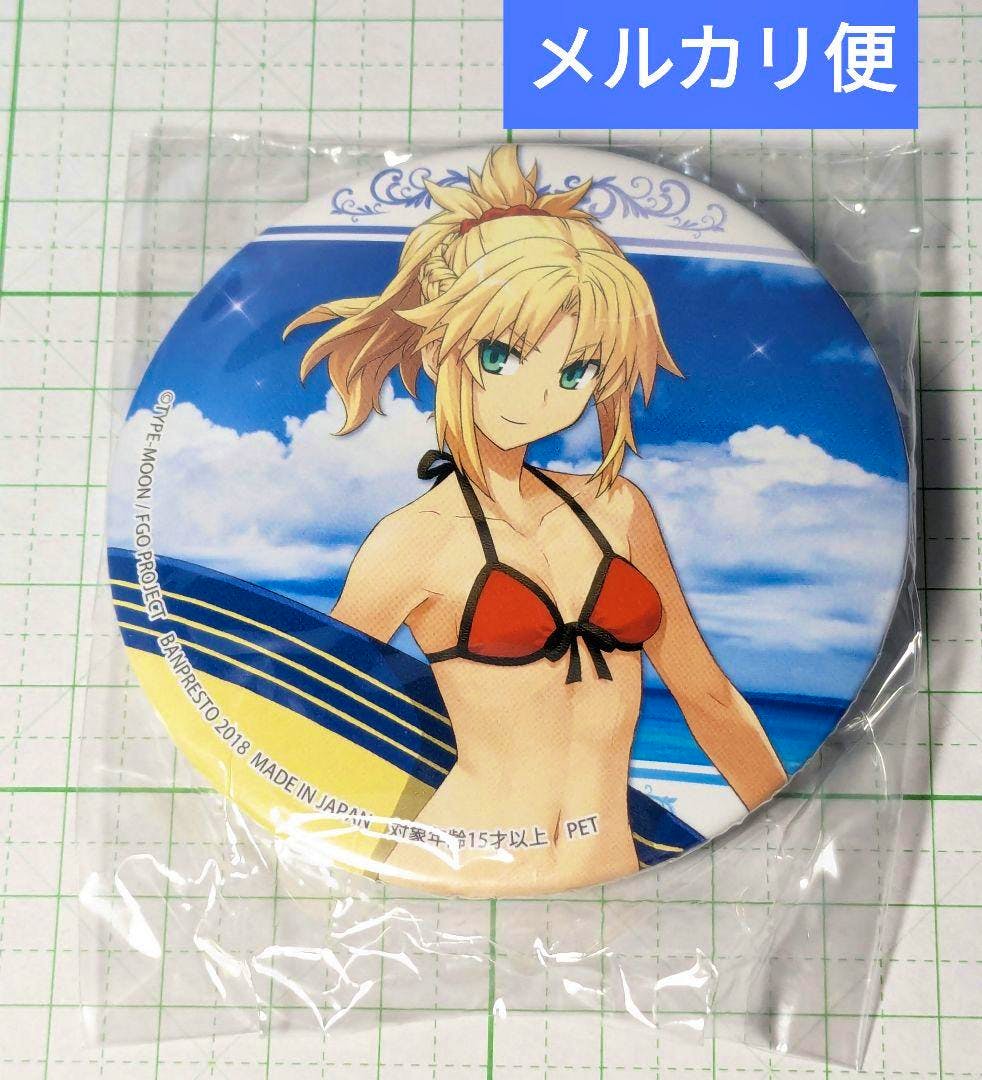 Front of a round can badge showing FGO character Mordred in a red swimsuit against a beach background, inside clear plastic packaging on grid paper.