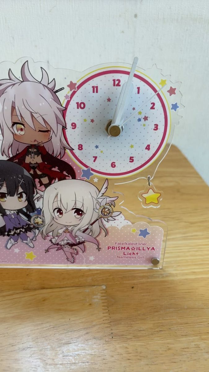 A clear acrylic standing clock with Fate/kaleid liner Prisma☆Illya Licht character art and a small round clock face.