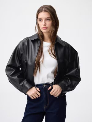 A model wearing a black faux-leather Harrington jacket over a white top.