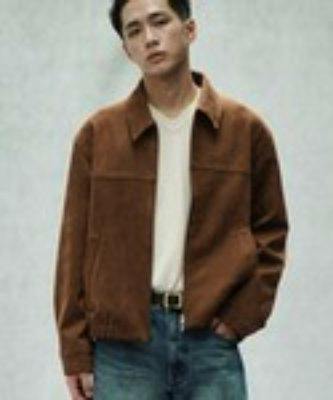 Man modeling a brown faux suede zip blouson jacket worn over a light t-shirt and blue jeans.