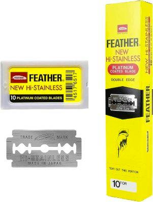 A plastic case labeled "FEATHER NEW HI-STAINLESS," a double-edge razor blade, and a tall yellow Feather box are shown.
