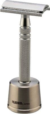 Feather stainless steel double-edged safety razor displayed upright in its metal stand.