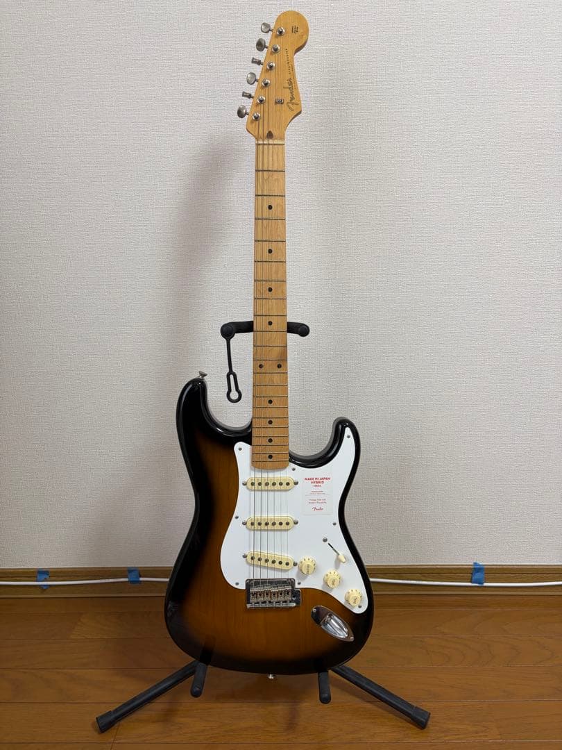 Fender Stratocaster Hybrid Series 50s electric guitar with sunburst finish standing on a guitar stand against a wall.