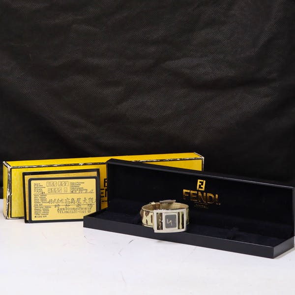 Fendi women's wristwatch with black dial and patterned leather strap displayed inside an open FENDI watch box with the yellow outer box and paperwork behind.