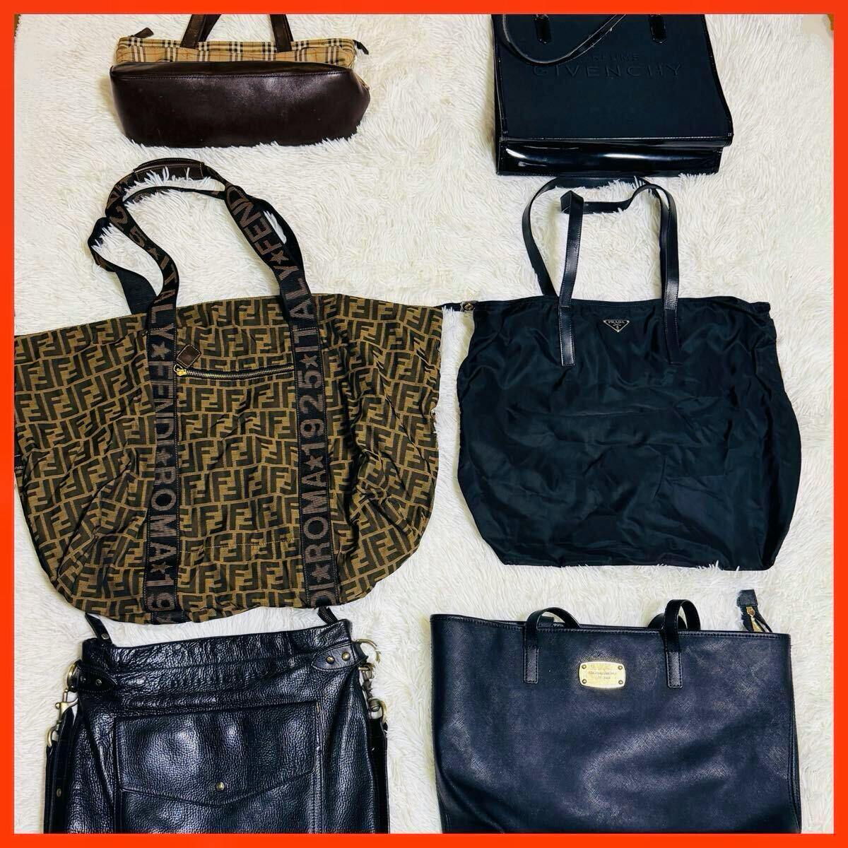 Six assorted handbags and totes laid flat on a white furry surface, shown together as a set.